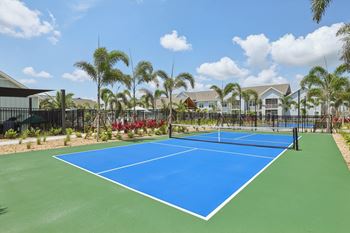 A blue tennis court surrounded by palm trees. at The Junction at Rockledge Apartments, Rockledge 32955
